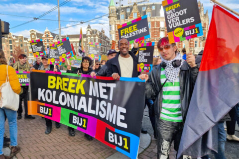 Demonstratie in Amsterdam met lijsttrekker Edson Olf achter een spandoek dat zegt: ‘Breek met kapitalisme’