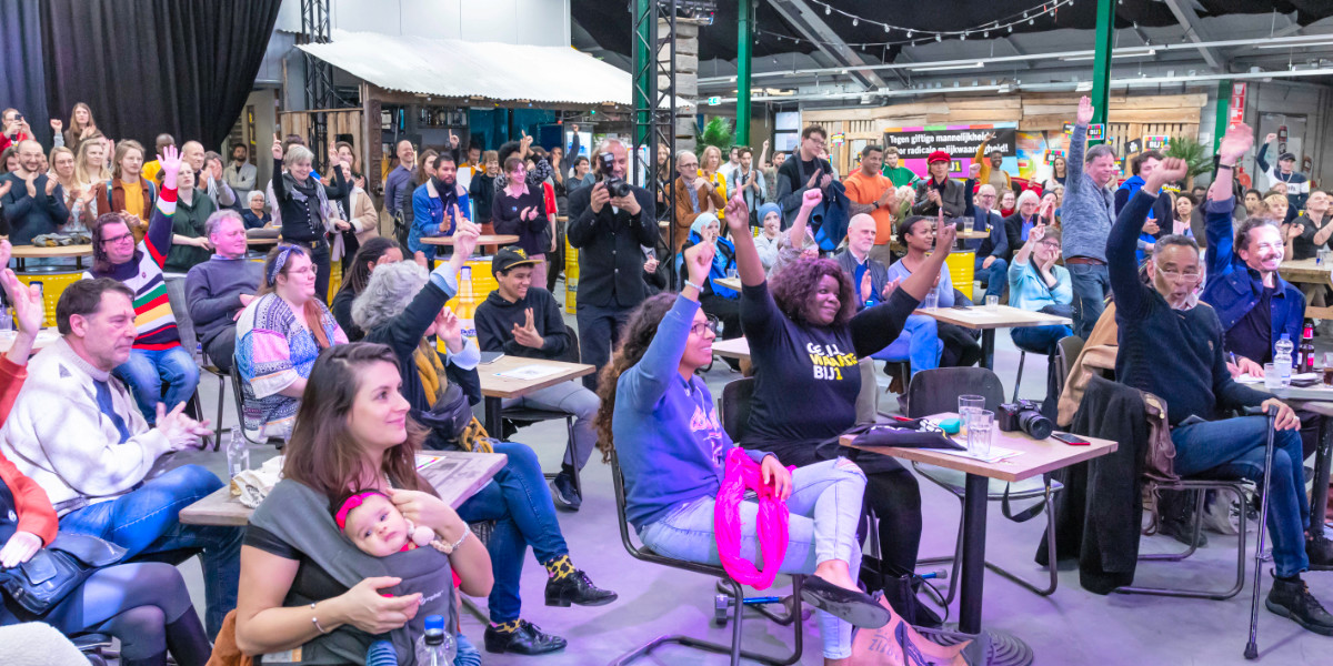 BIJ1 algemene ledenvergadering met grote diverse groep mensen in een zaal